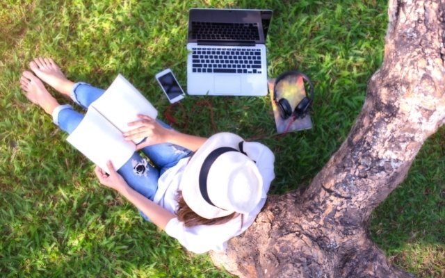 a woman sitting under a tree and reading a book