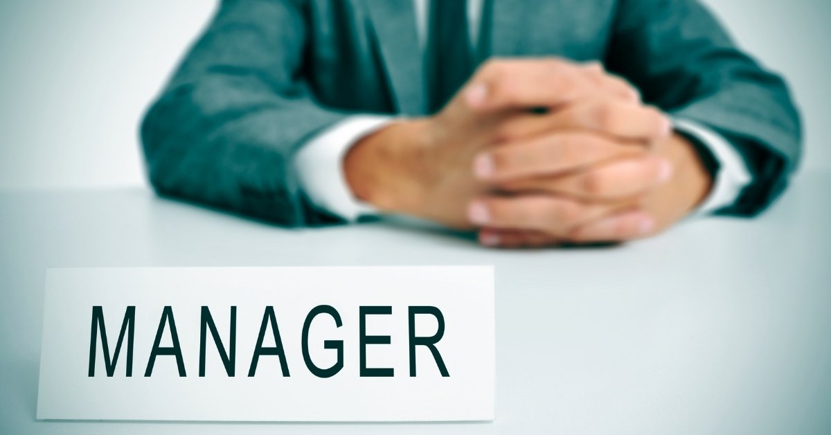 a manager sitting near a table and holding his hands together while thinking