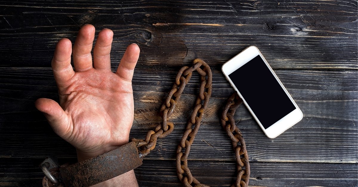 a person's hand tied to his mobile phone to represent the addiction to mobile phone 