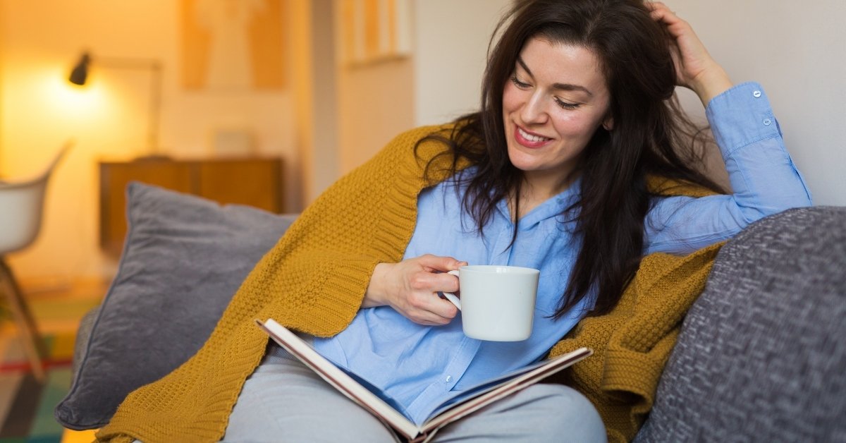 a woman reading book and drinking coffee during her leisure time